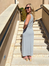 Woman in a blue patterned dress standing on stone steps outdoors.