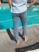 Person wearing light blue jeans standing by a pool