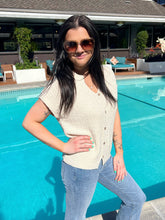 Woman wearing sunglasses and a beige top by a pool
