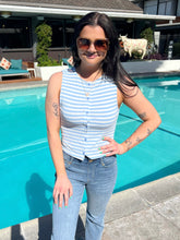 Woman standing by a pool wearing a striped shirt and jeans.