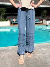 Person wearing blue ruffled pants standing by a pool