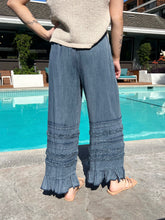 Person wearing blue ruffled pants by a pool