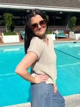 Woman wearing sunglasses and a beige top by a pool