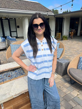 Woman wearing sunglasses and a blue and white striped shirt in an outdoor setting