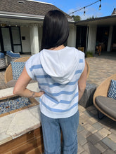 Person wearing a striped shirt and jeans standing on a patio