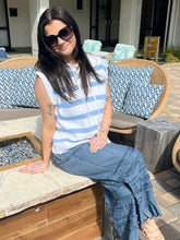 Woman sitting on a patio with outdoor furniture and cushions.