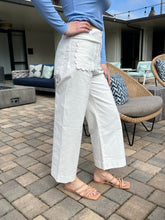 Person wearing white pants and a blue top standing on a patio.