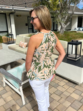 Woman wearing a patterned top and white pants standing in an outdoor setting.