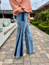 Person wearing blue flared jeans with a peach top on a patio.