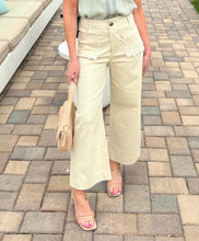 Person wearing beige pants with white buttons on a paved outdoor area