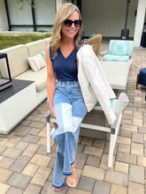 Woman sitting on a chair outdoors wearing sunglasses and casual clothing.