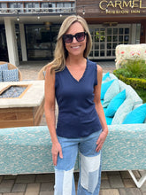 Woman in a blue top and jeans standing in front of a building with 'Carmel Mission Inn' sign.