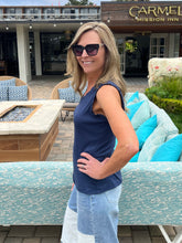 Woman in sunglasses and a blue top standing in front of outdoor furniture with 'Carmel Mission Inn' in the background.