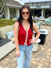 Woman in a red top and blue jeans standing outdoors on a patio.