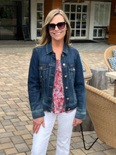 Woman wearing a denim jacket and sunglasses outdoors on a patio