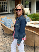 Woman standing outdoors by a patio with wicker furniture and a fire pit.