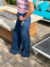 Person wearing blue jeans standing on a patio with outdoor furniture in the background