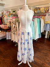 Mannequin wearing a white sweater tank with a blue and white floral skirt in a store setting.