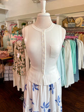 Mannequin wearing a white sweater tank with a blue and white floral skirt in a store setting.