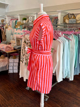 Mannequin wearing a red and white striped dress in a store setting with racks of clothes in the background.