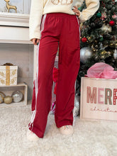 Person wearing red track pants standing in a Christmas themed area of a home.