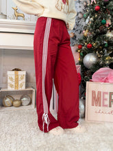Person wearing red track pants standing in a Christmas themed area of a home with a tree and some gifts.