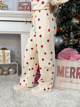 Person wearing white and red polka dot sweatpants standing in front of a Christmas tree. 