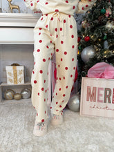 Person wearing white and red polka dot sweatpants standing in front of a Christmas tree. 