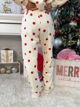 Person wearing white and red polka dot sweatpants standing in front of a Christmas tree showing back of pants.