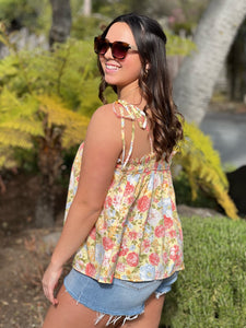 Women wearing yellow floral tank top showing back view. 