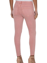 Woman wearing light pink skinny jeans and showing the back view  of body .