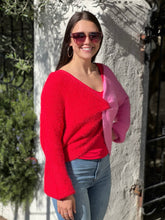 Women posing with hand on hip in a red and pink sweater.